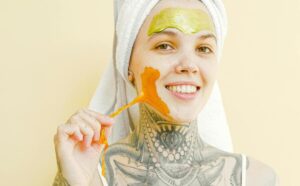 Smiling woman applying an orange face mask