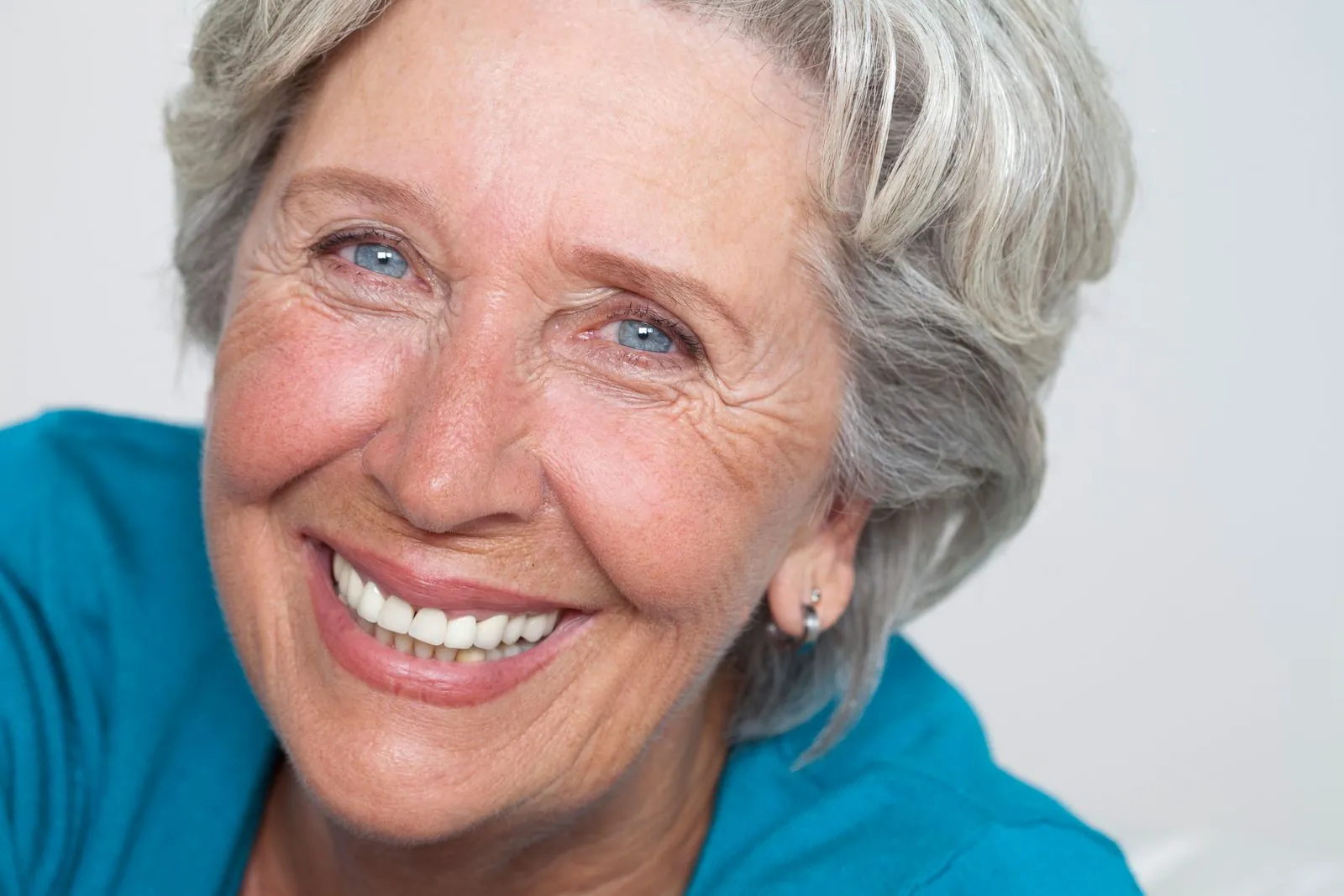 Smiling older woman with crow's feet fanning out from the outer corners of both eyes