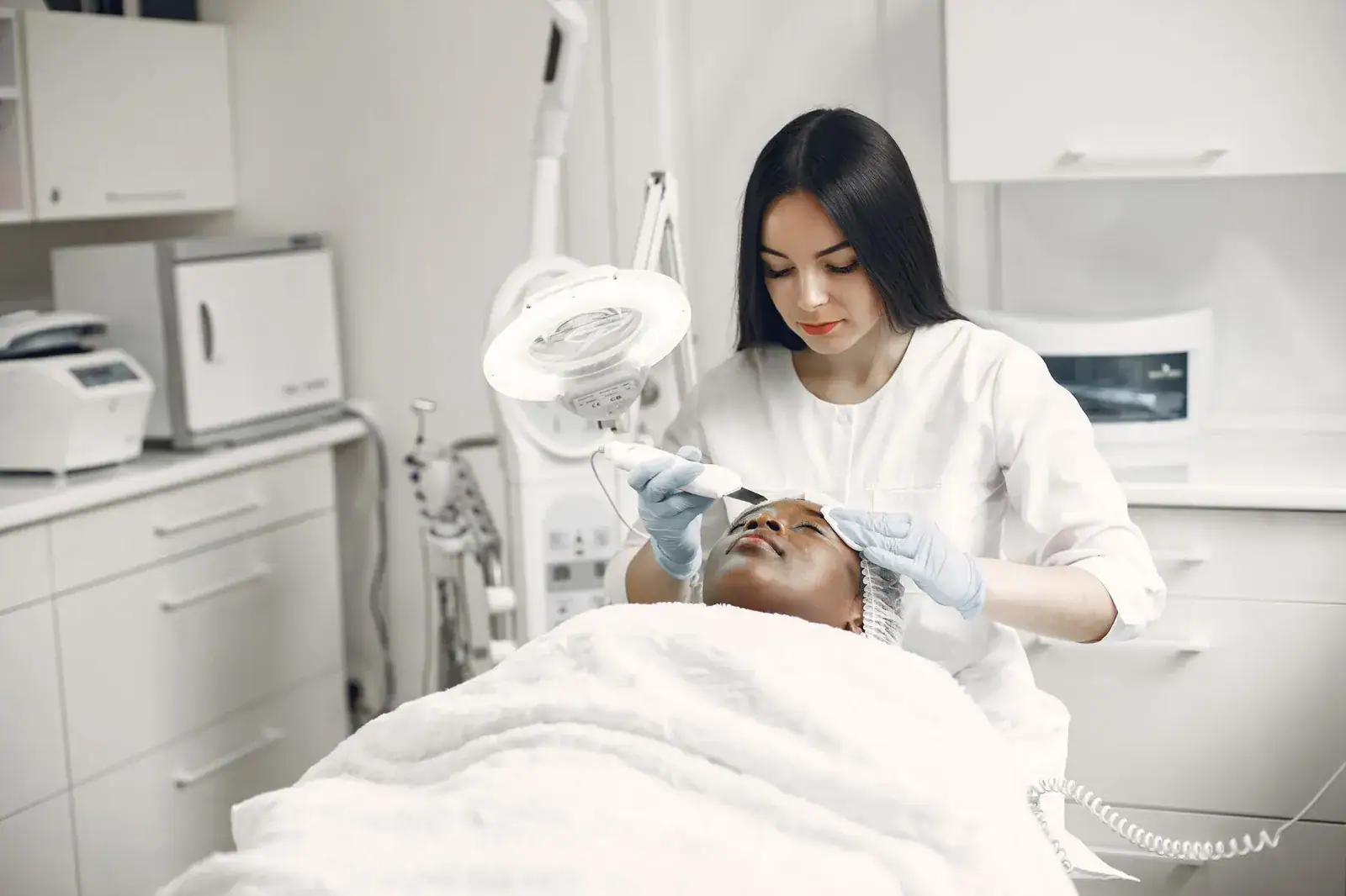 A practitioner performing a facial skin procedure in a clinic treatment room